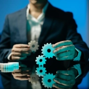 Homme d'affaires connectant des rouages sur un bureau réfléchissant, symbolisant la straté