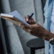 Vue recadrée d'un homme afro-américain prenant des notes près de la fenêtre de la chambre
