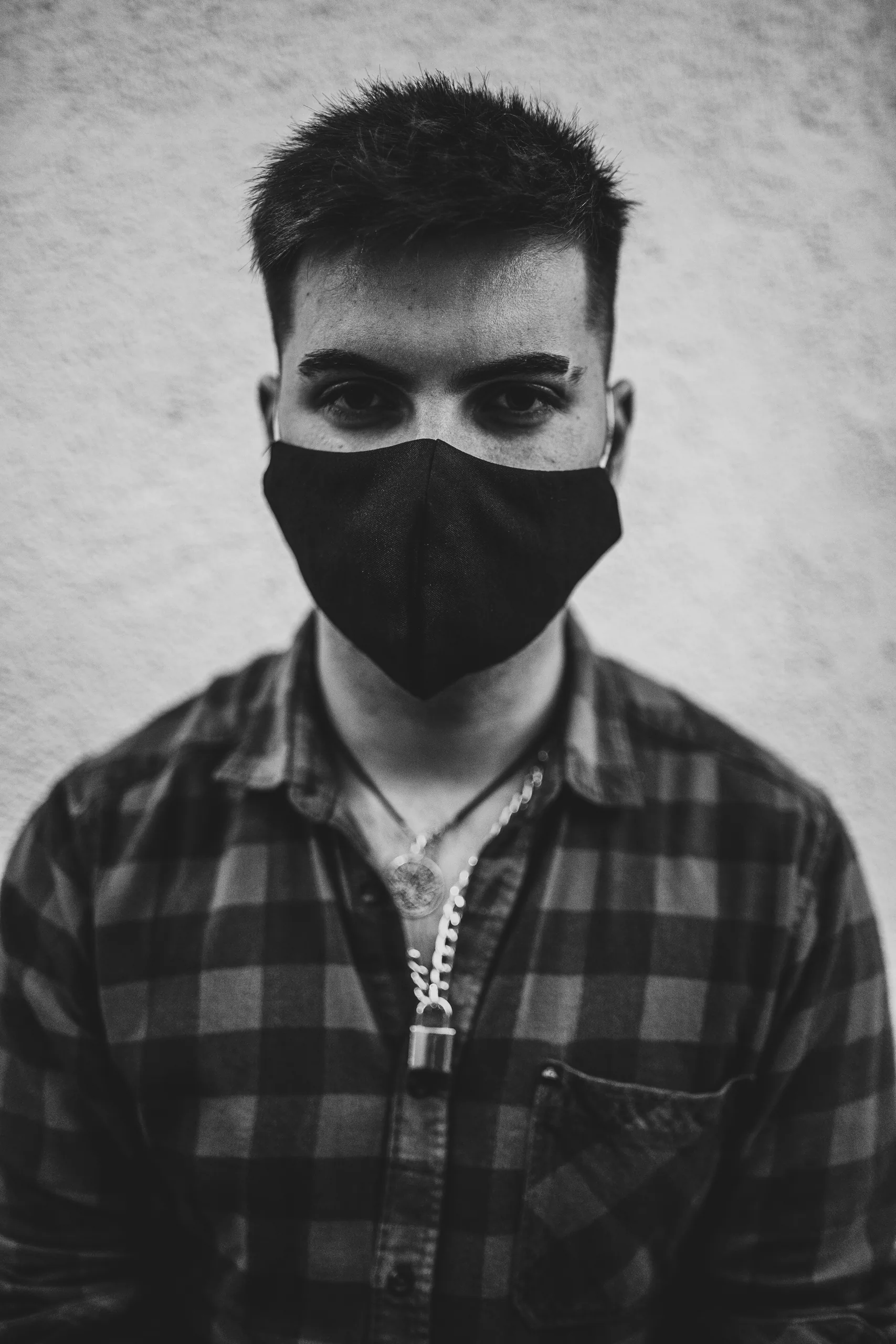 Une photo verticale en niveaux de gris d'un jeune homme espagnol portant un masque facial Une photo verticale en niveaux de gris d'un jeune homme espagnol portant un masque facial