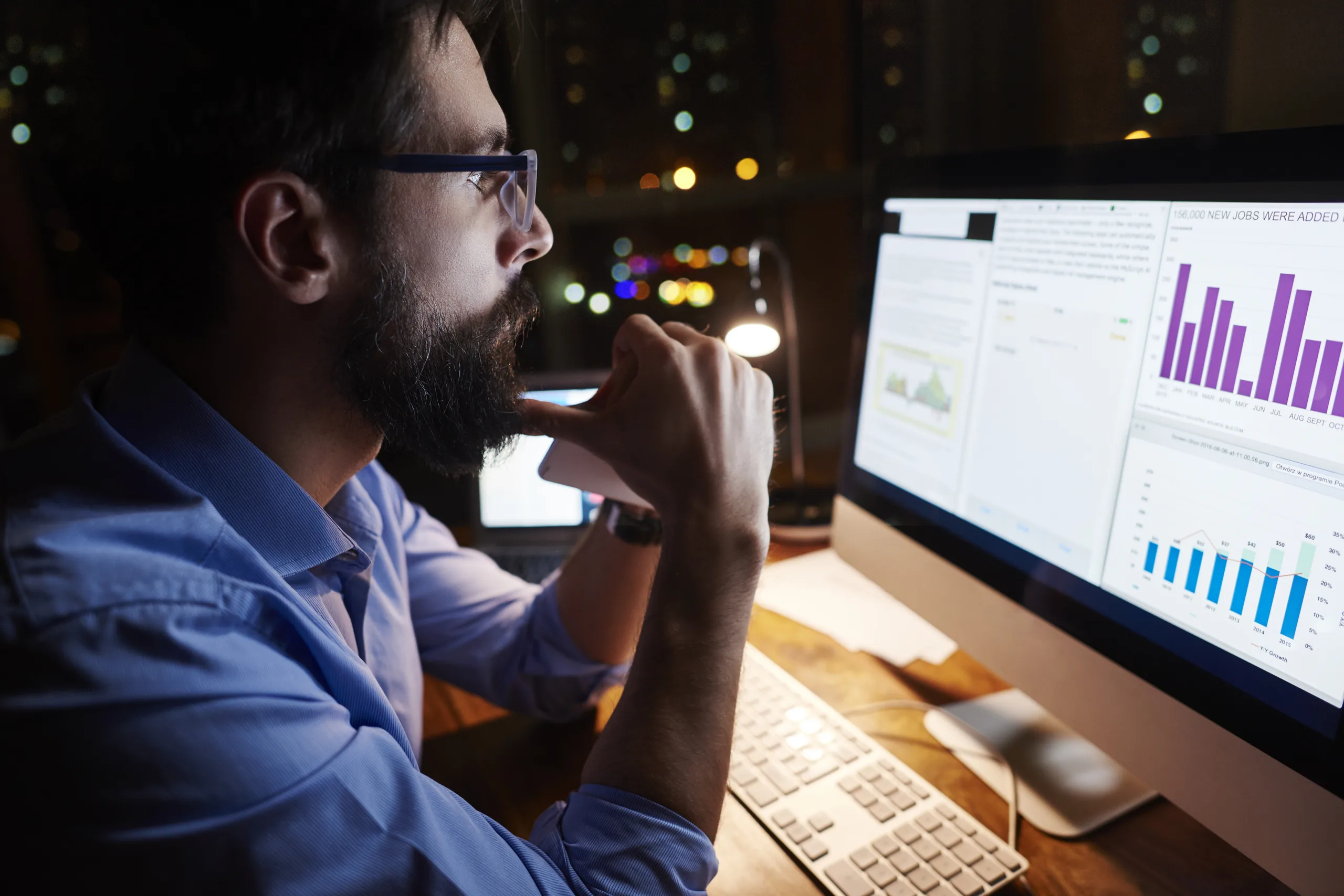 Jeune homme d'affaires regardant un ordinateur sur le bureau la nuit Jeune homme d'affaires regardant un ordinateur sur le bureau la nuit